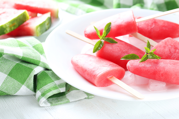 Watermelon popsicle on plate on white wooden table